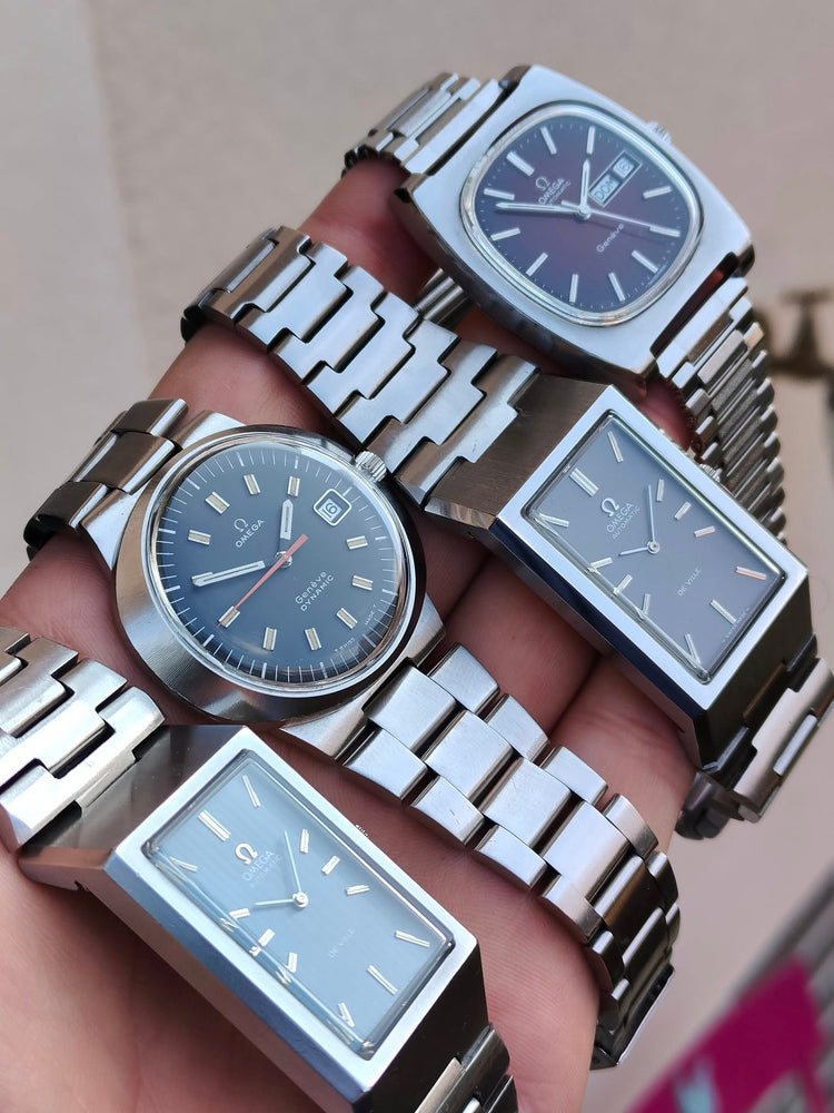 Vier Omega-Vintage-Uhren aus den 1970er-Jahren gemeinsam in einer Hand, darunter Omega Genève und De Ville