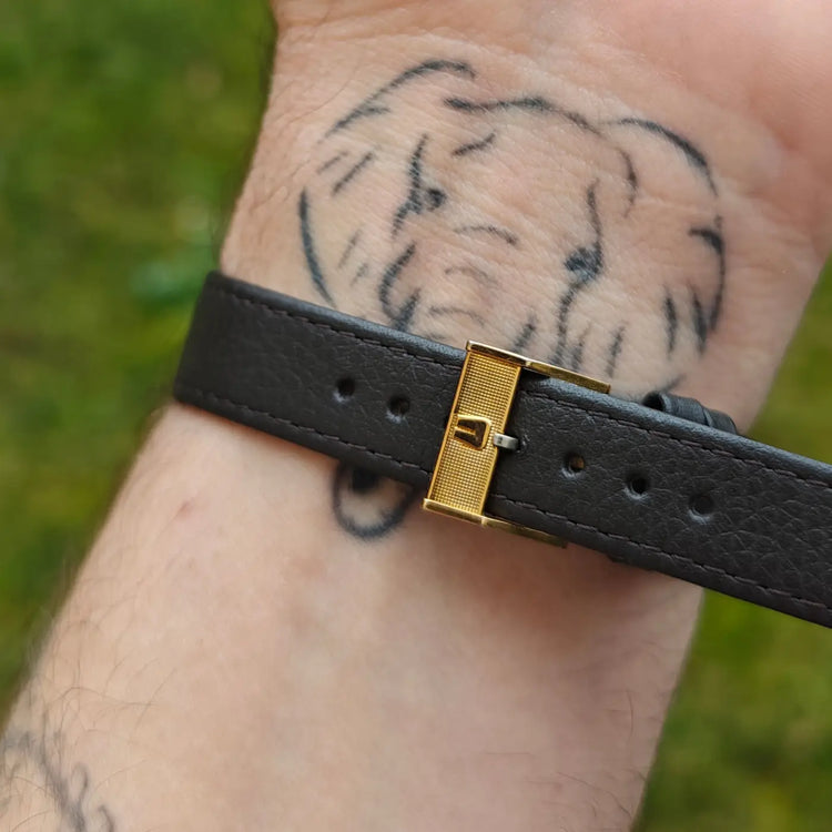 Detailaufnahme von schwarzem Lederband und goldfarbener Schließe einer Universal Genève mit Kaliber 42