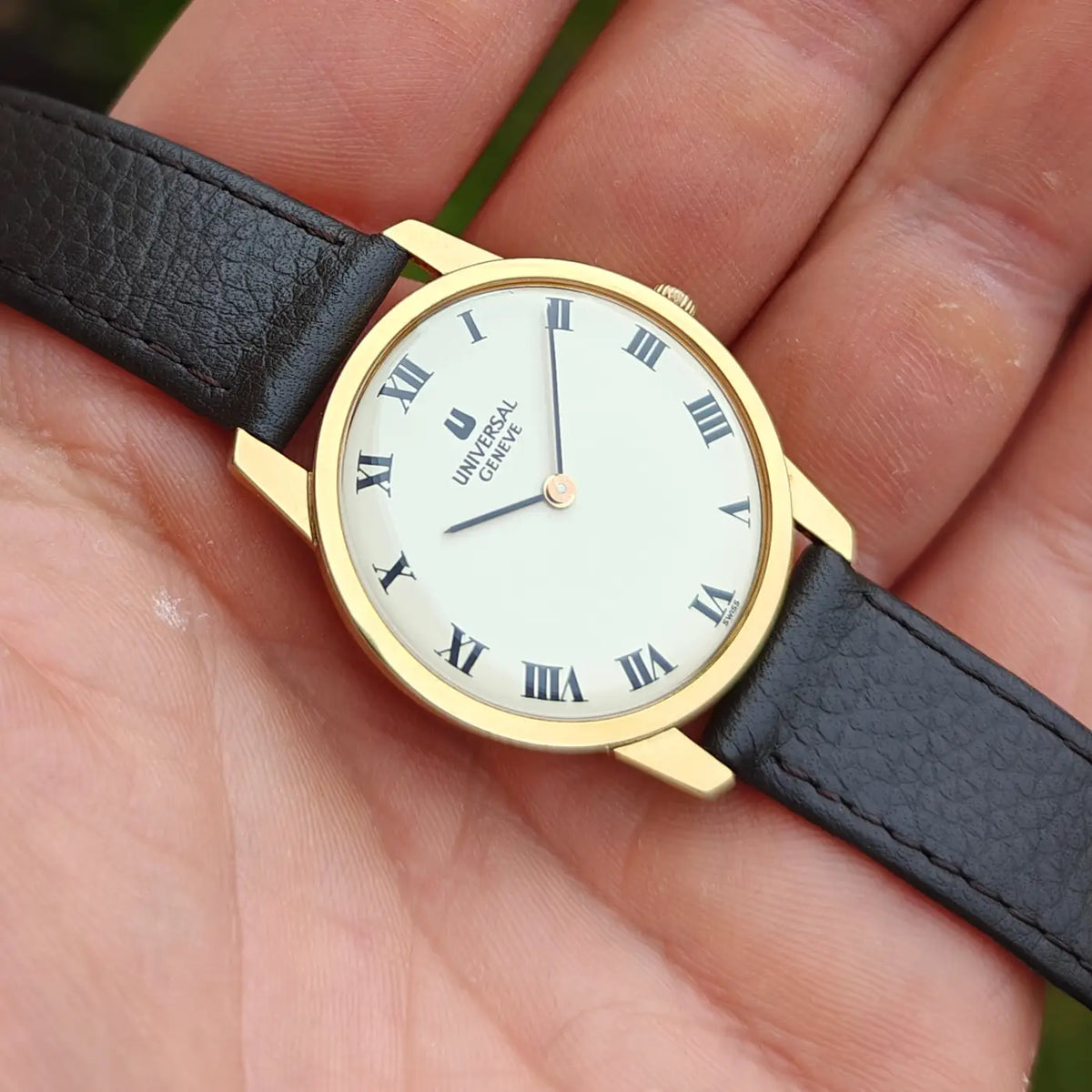 Universal Genève ultraflache Uhr mit weißem Zifferblatt, römischen Ziffern und strukturiertem schwarzem Lederband