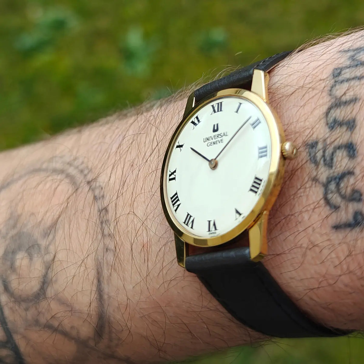 Universal Genève elegante Armbanduhr mit weißem Zifferblatt, schwarzen römischen Ziffern und schwarzem Lederband